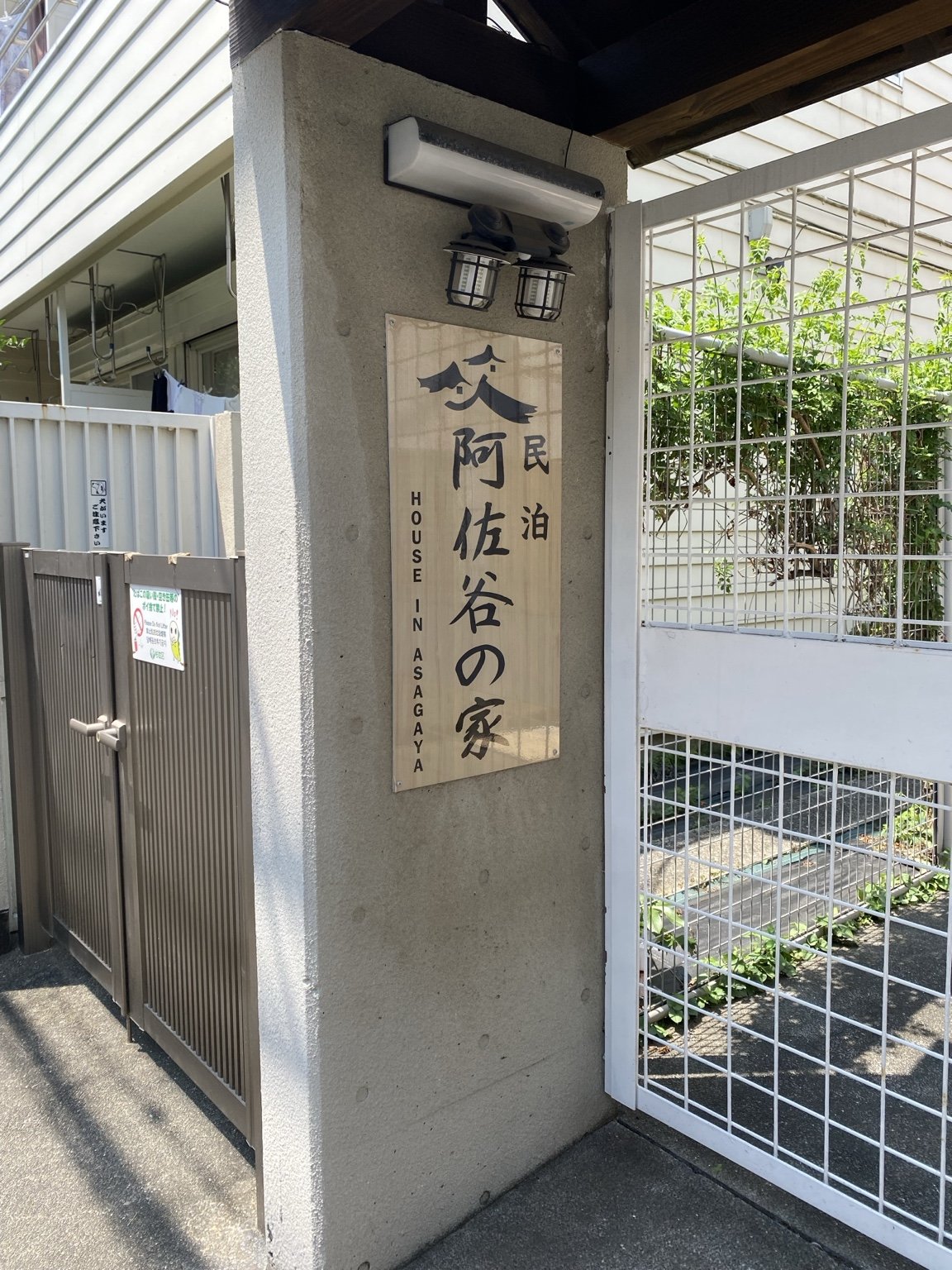 A wooden sign reading "House in Asagaya" at the gate of a guesthouse