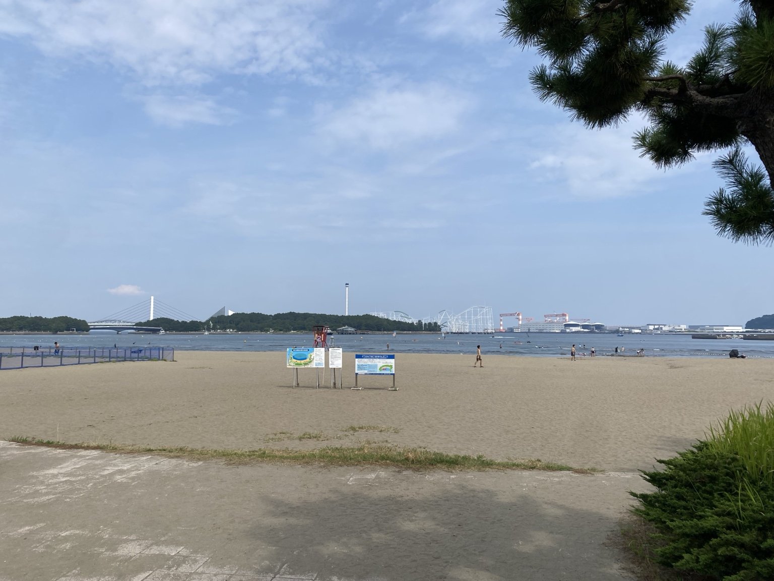 海の公園の砂浜。対岸に八景島シーパラダイスのコースターと工場のクレーンが並ぶ