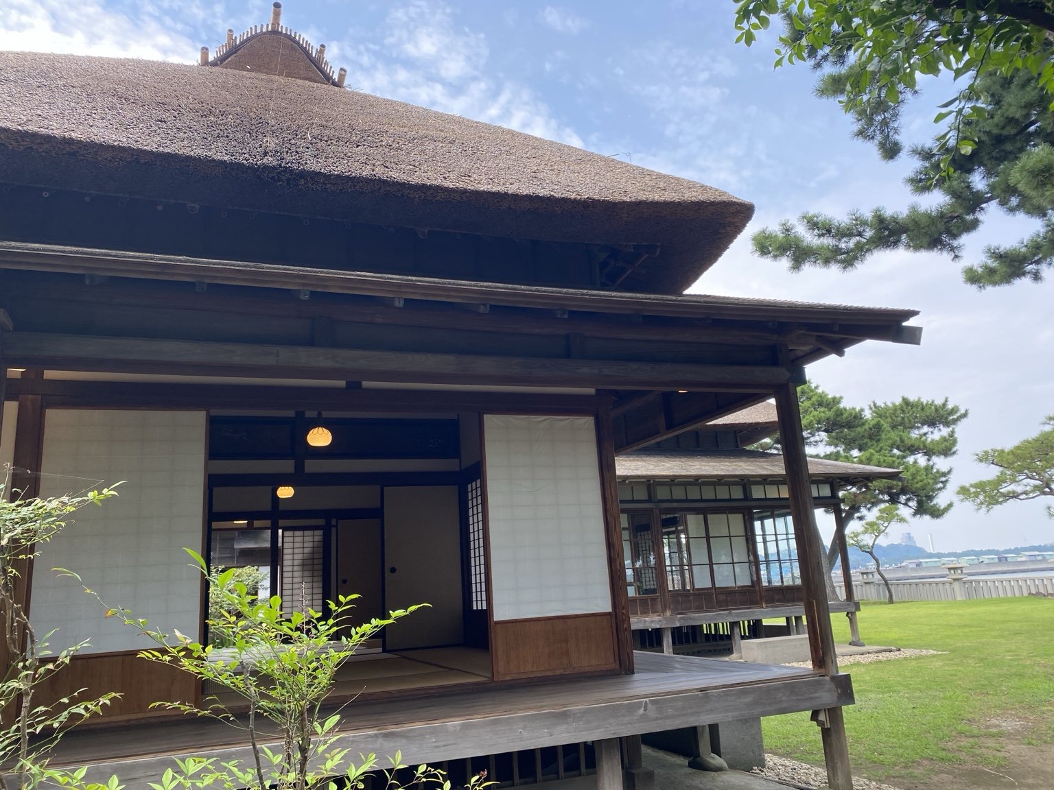 茅葺き屋根と縁側が続く旧伊藤博文金沢別邸の外観。障子が開け放たれ座敷が見えている